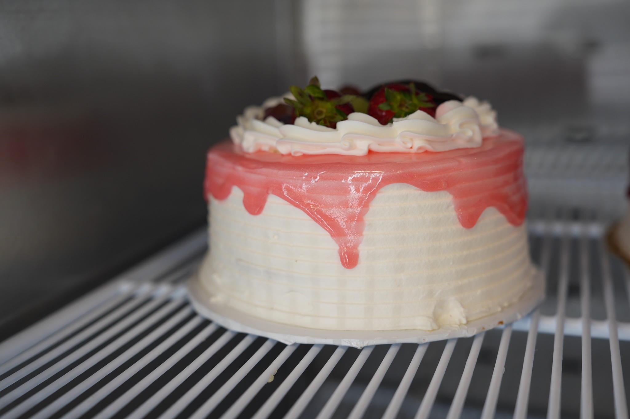 Pastel blanco con cobertura rosada y fresas