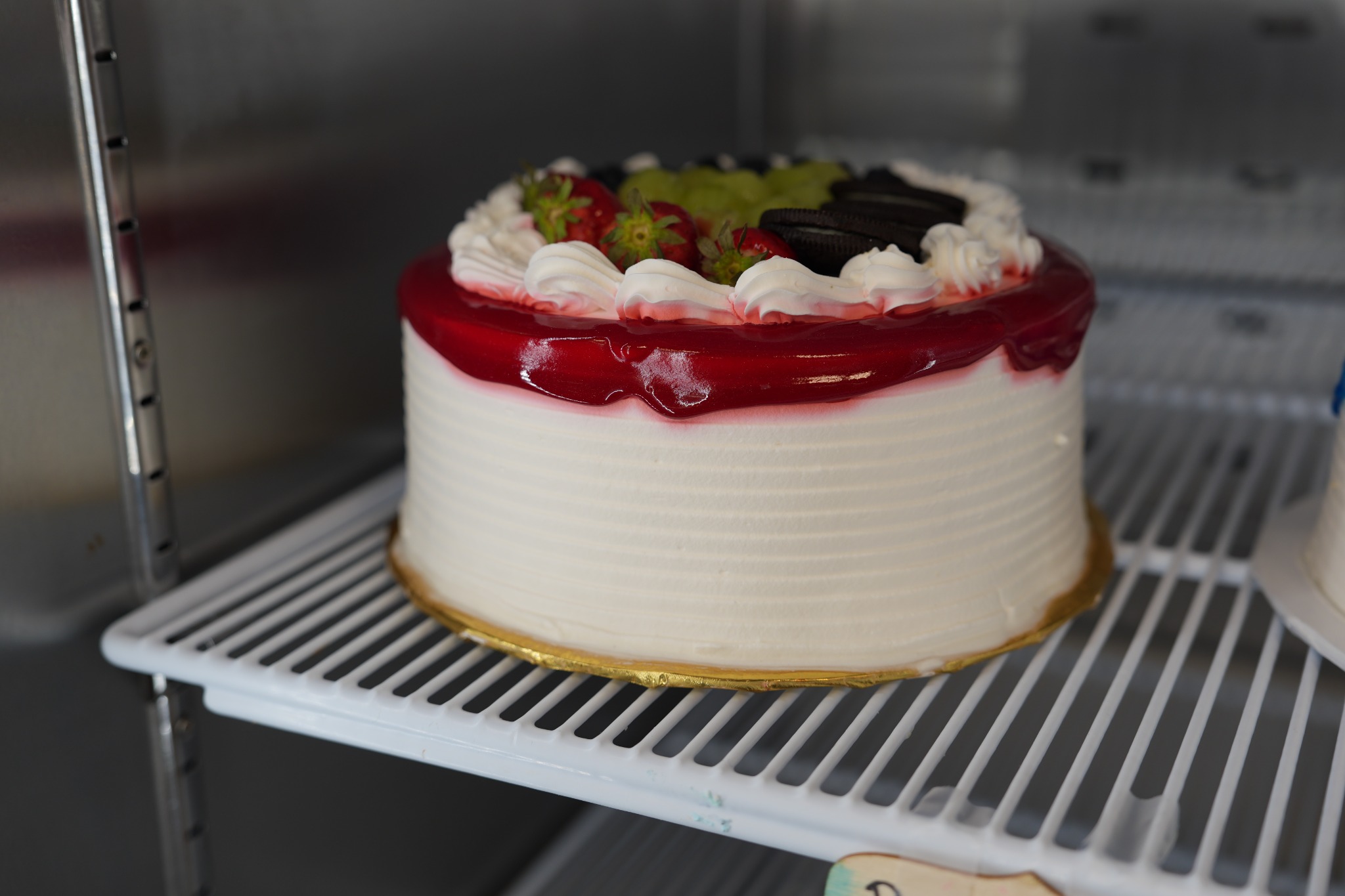 Pastel blanco con cobertura roja, fruta y galletas