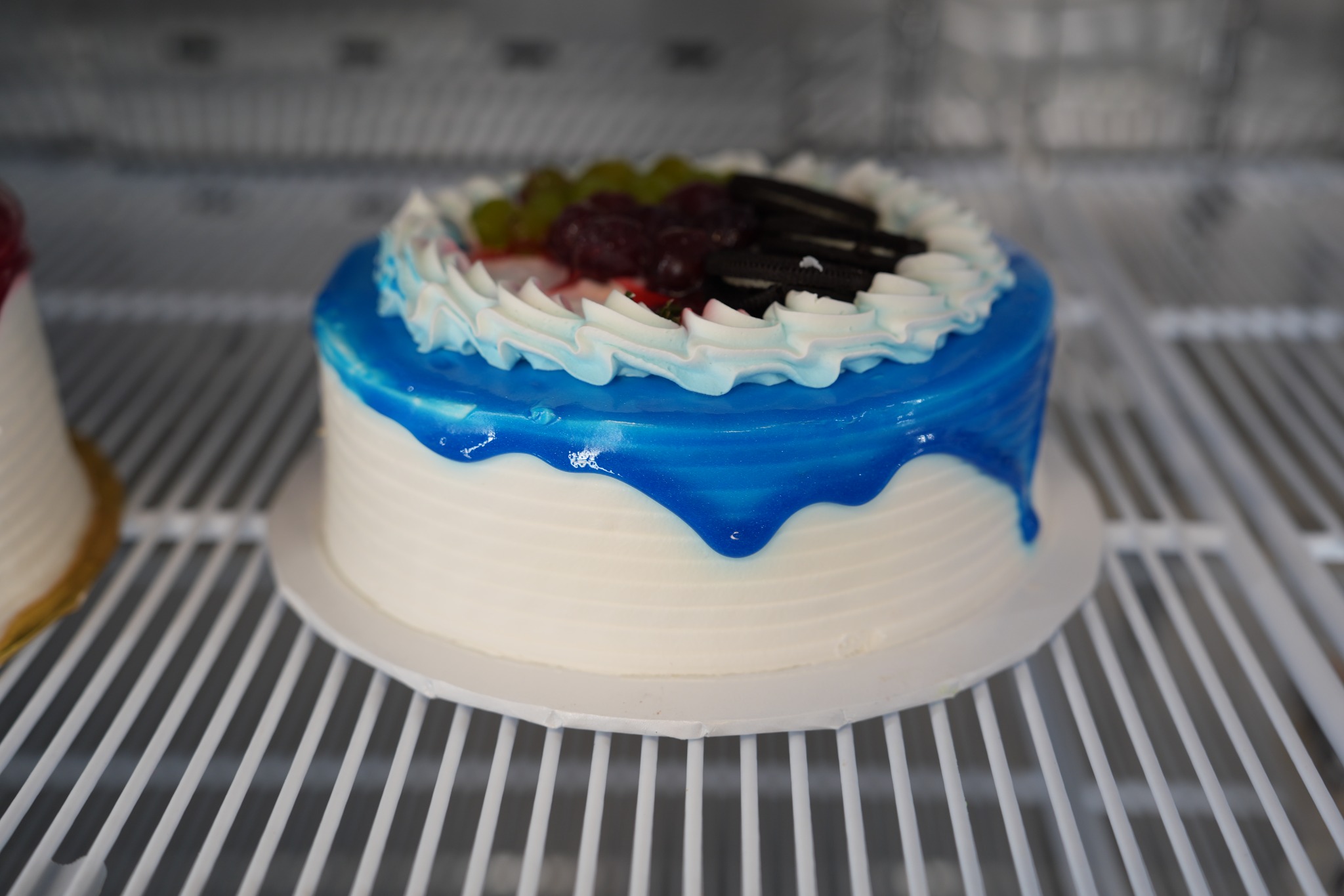 Pastel blanco con cobertura azul, fruta y galletas